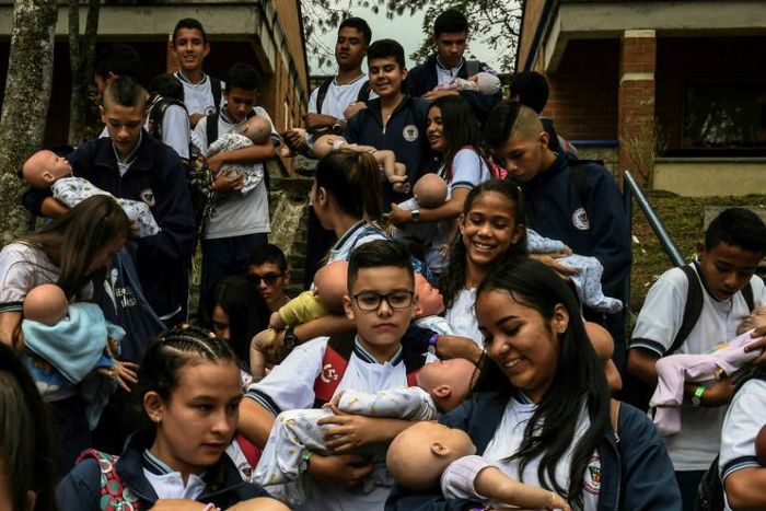Students carry their "babies" during a break at a school in Caldas municipality, Colombia on May 17, 2019