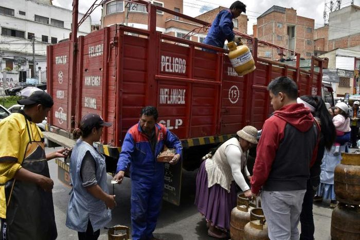 A man downloads gas cylinders from a truck in La Paz as life gets back to normal after weeks of protests