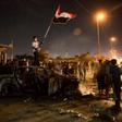 An Iraqi protester waves the national flag as he stands atop a burnt out police vehicle outside the local government headquarters in the southern city of Basra on Friday