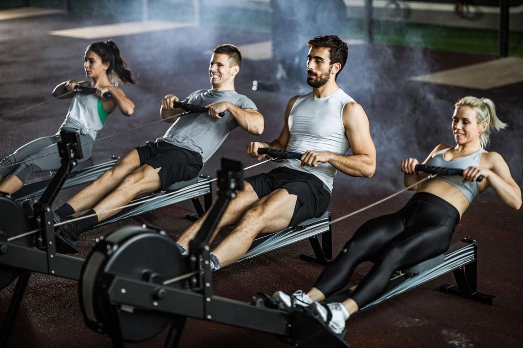 Group of athletes exercising on rowing machines in a gym.