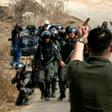 A Palestinian protester makes an insulting gesture to Israeli border guards during a protest against construction of an Israeli outpost near an Israeli settlement in the occupied West Bank