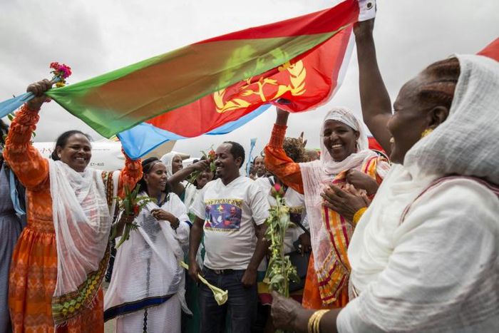 Joy: Eritrean women hold aloft the national flag in July 2018 to welcome passengers arriving from Ethiopia, a key step in the two rivals' path to peace