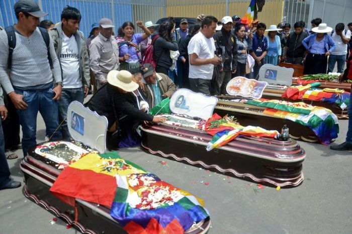 Relatives mourn by the coffins of protesters killed during protests in the Bolivian town of Sacaba on November 16, 2019