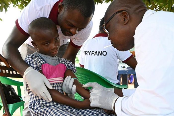 A health worker takes blood from a child in the Ivorian village of Paanenefla -- the sample will be tested for sleeping sickness