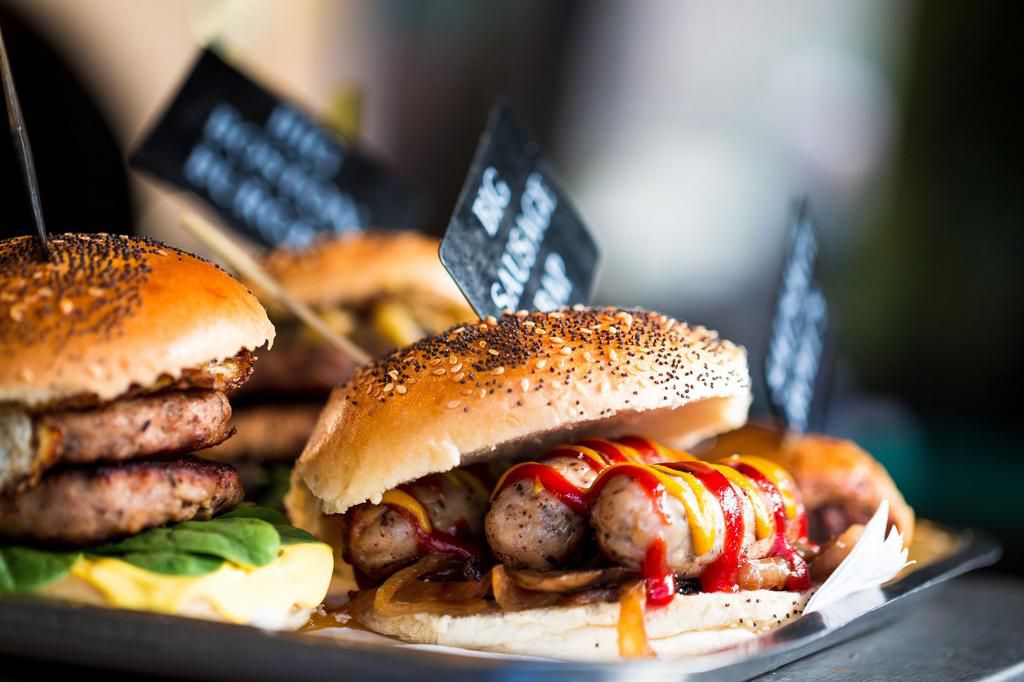 Close up of fresh flame grilled burgers with sausages displayed in a row at food market