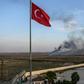 Smoke rises from the Syrian town of Tal Abyad, in a picture taken from the Turkish side of the border where the Turkish flag is seen in Akcakale on October 10, 2019, on the second day of Turkey's military operation against Kurdish forces