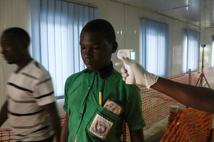 A health official checks the temperature of a boy from Uganda on his way to school in Uganda. The daily inspections at the border are a safeguard against Ebola