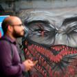 A man walks by graffiti depicting a demonstrator with an injured eye, in clear reference to those hurt in recent clashes, on November 18