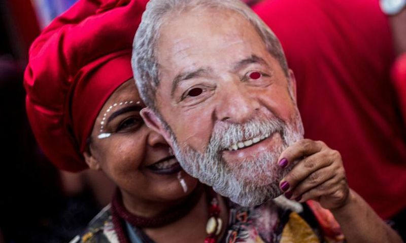 A supporter of Brazil's Workers Party holds a mask with the face of imprisoned former Brazilian president Luiz Inacio Lula da Silva