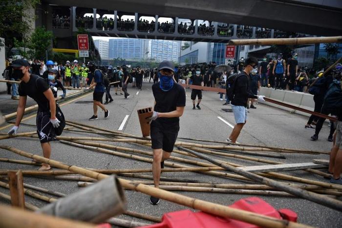 Thousands of demonstrators, many wearing hard hats and gas masks, marched through the industrial Kwun Tong area, where they were blocked by dozens of riot police with shields and batons