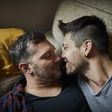 Affectionate gay couple resting on couch at home
