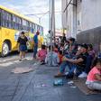 Migrants, mostly from Mexico, are pictured sitting on the ground waiting near the Paso del Norte Bridge at the Mexico-US border, in Ciudad Juarez, Mexico, on September 12, 2019.
