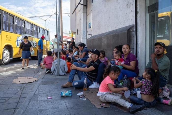 Migrants, mostly from Mexico, are pictured sitting on the ground waiting near the Paso del Norte Bridge at the Mexico-US border, in Ciudad Juarez, Mexico, on September 12, 2019.