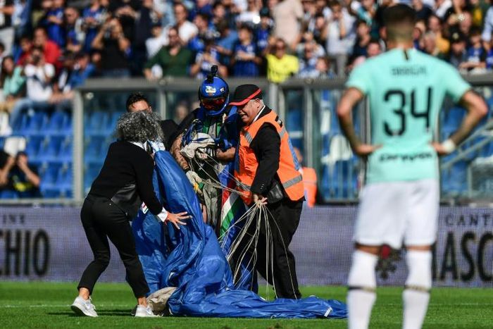 Security staff evacuate a parachutist who landed on the pitch at Sassuolo's stadium in Reggio-Emilia during a game against Inter Milan
