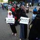 Sudanese protesters hold signs that read: "Take your uncles and aunts with you" and "You who's going home, give a lift to a couple of people"