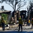 Firefighters gather their hoses near destroyed homes along North Tigertail Road near the Getty Center in Los Angeles on October 29