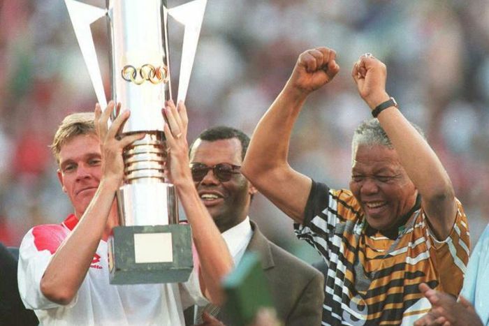 Then South Africa president Nelson Mandela (R) celebrates as captain Neil Tovey (L) holds the Africa Cup of Nations trophy after defeating Tunisia in the 1996 final