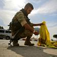 A Turkish-backed Syrian fighter burns the flag of the Kurd-led SDF