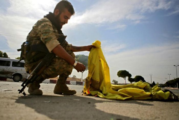 A Turkish-backed Syrian fighter burns the flag of the Kurd-led SDF