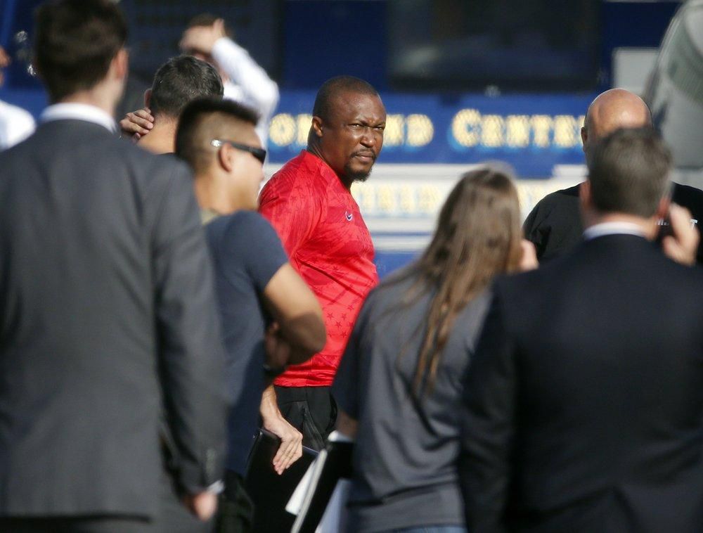 U.S. federal agents hold a detainee, center, at a downtown Los Angeles parking lot after predawn raids that saw dozens of people arrested in the L.A. area Thursday, Aug. 22, 2019 [AP Photo/Reed Saxon]