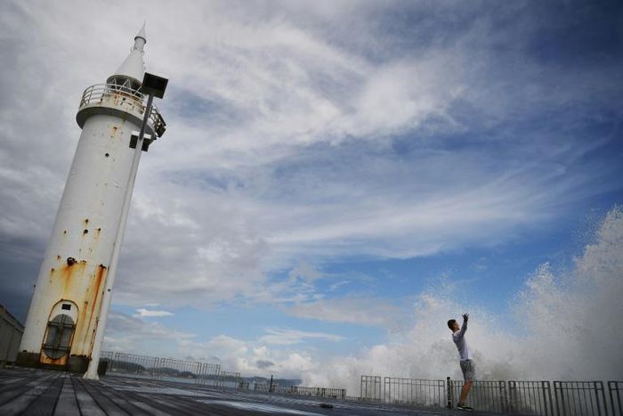 A man reacts as waves crash against the seafront on Enoshima Island on the coast of Kanagawa prefecture, southwest of Tokyo. Japan is bracing for a super typhoon this weekend as strong as the fiercest seen in decades