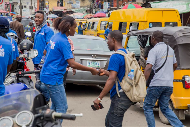 A female canvasser providing flyer to a passer-by on Obafemi Awolowo Way, Ikeja during the road show.