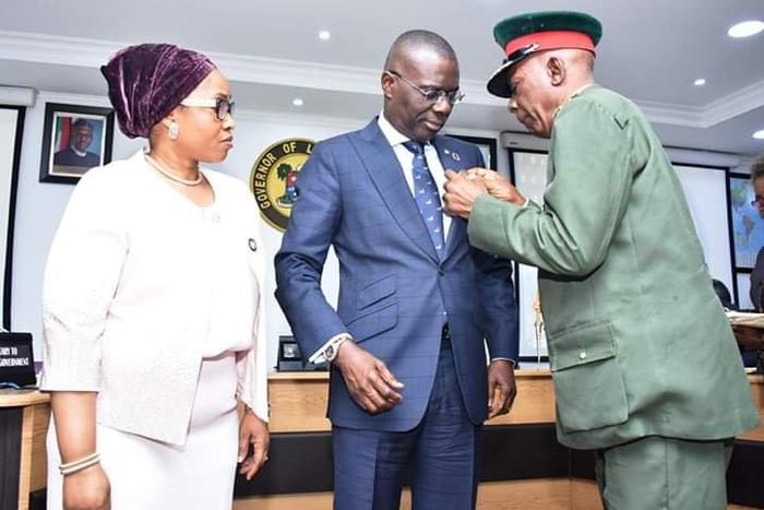 Lagos State Governor, Mr. Babajide Sanwo-Olu (middle) being decorated with the Armed Forces Remembrance Day Emblem by the Chairman, Nigerian Legion, Lagos State Chapter, Col. Samuel Akande (Rtd) (right), while Commissioner for Home Affairs, Mrs Uzamat ...