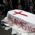A member of the Rwanda National Congress opposition party puts pictures of slain party founder Patrick Karegeya next to a mock coffin reading "Kagame's victims" during a demonstration outside the Rwandan embassy in Pretoria