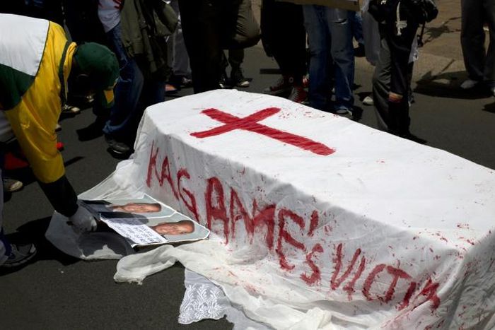 A member of the Rwanda National Congress opposition party puts pictures of slain party founder Patrick Karegeya next to a mock coffin reading "Kagame's victims" during a demonstration outside the Rwandan embassy in Pretoria