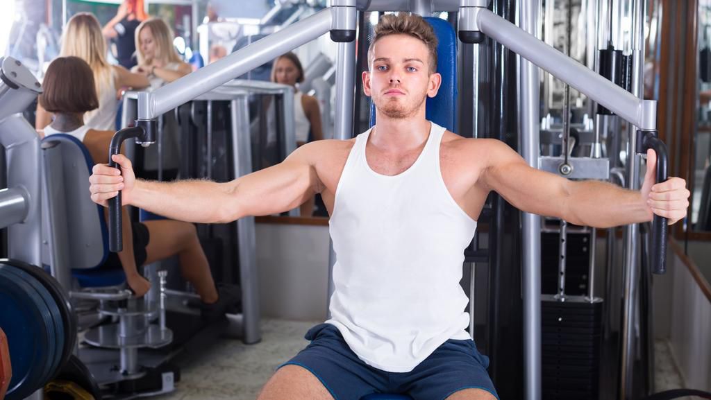 Young man using fly machine in gym