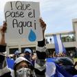 A student carries a sign reading "Let the water pass" during a protest of students and relatives of political prisoners, in Managua on Tuesday