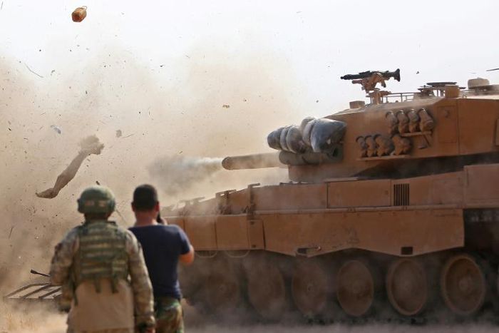 Turkish soldiers at a position east of Ras al-Ain watch as a tank fires on positions held by Kurdish-led forces