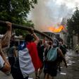 Demonstrators hold up a hose as flames engulf the Pedro de Valdivia University following a protest against the government of Chilean President Sebastian Pinera in Santiago, on November 8, 2019.Unrest began in Chile last October 18 with protests against...