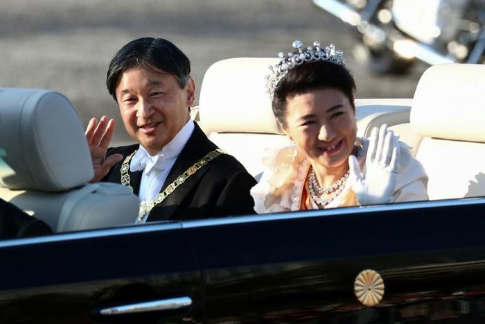 Japan’s Emperor Naruhito  and Empress Masako wave during their royal parade in Tokyo