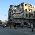 People walk near heavily damaged buildings in the rebel-held city of Idlib in northwestern Syria on September 16, 2019