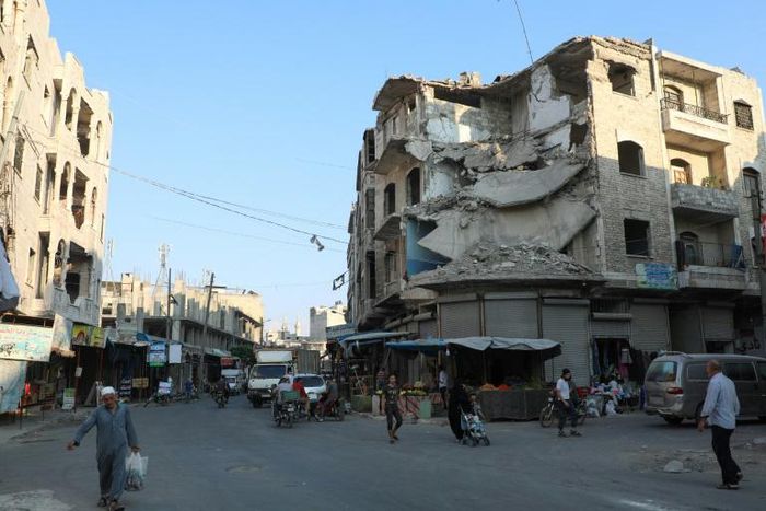 People walk near heavily damaged buildings in the rebel-held city of Idlib in northwestern Syria on September 16, 2019
