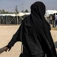 A French woman held at Al-Hol camp holds a child by the hand