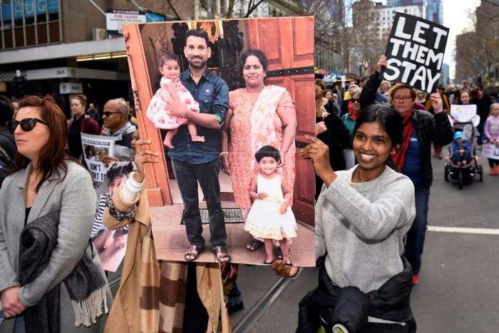 Protesters hold up placards in Melbourne during a rally in support of the Tamil refugee family