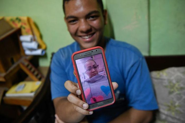 Venezuelan Frankeiber Hernandez, 18, whose parents emigrated to Peru, shows a picture of his mother on his mobile phone at home in the Catia neighborhood in Caracas