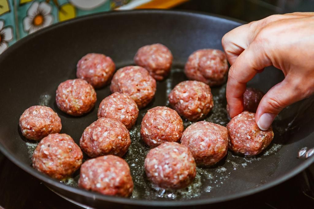 Cropped Image Of Hand Frying Meatballs In Pan