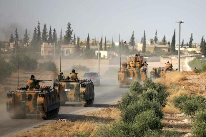 Turkish troops drive their armoured personnel carriers through the village of Qirata on the outskirts of the northern city of Manbij near the Turkish border, on October 14, 2019