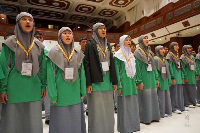 Students assembled in a university auditorium to practice ballads specially written for the pontiff