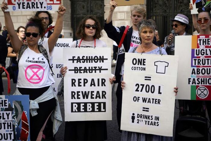 Extinction Rebellion argues that fast fashion is hugely wasteful hold up anti-fashion placards as they block a road on the third day of London Fashion Week in London on September 15, 2019.