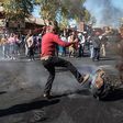 A man kicks a burning piece of furniture during a riot in the Johannesburg suburb of Turffontein on September 2, 2019 [Michele Spatari/AFP]