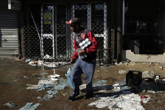 A looter makes off with goods from a store in Germiston, east of Johannesburg, South Africa [Themba Hadebe/The Associated Press]