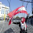 A Lebanese demonstrator waves the national flag while security forces stand by