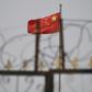 The Chinese flag flies behind razor wire at a housing compound in Yangisar, south of Kashgar, in China's western Xinjiang region