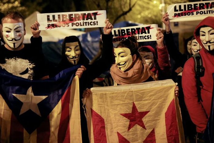 Demonstrators wear Guy Fawkes masks, hold Catalan pro-independence "Estelada" flags and placards reading "Freedom for Political Prisoners" during a "Million Mask March" organised by Anonymous and other movements this week