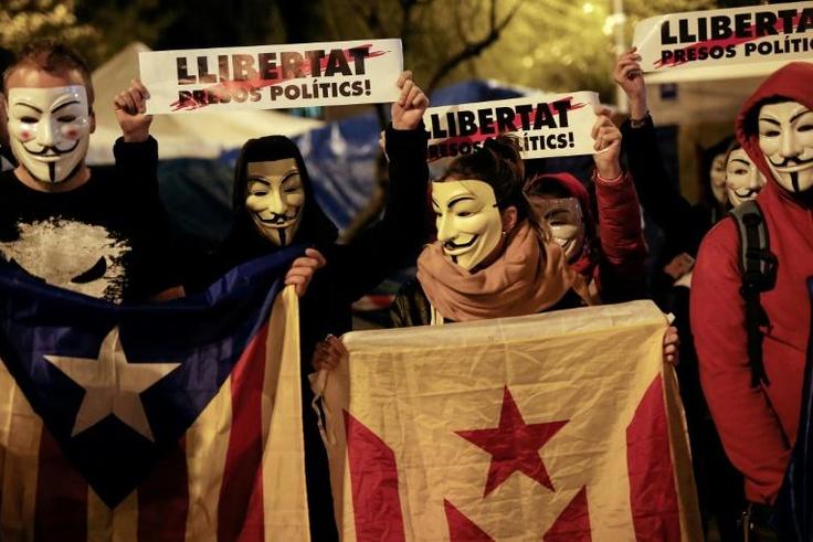 Demonstrators wear Guy Fawkes masks, hold Catalan pro-independence "Estelada" flags and placards reading "Freedom for Political Prisoners" during a "Million Mask March" organised by Anonymous and other movements this week