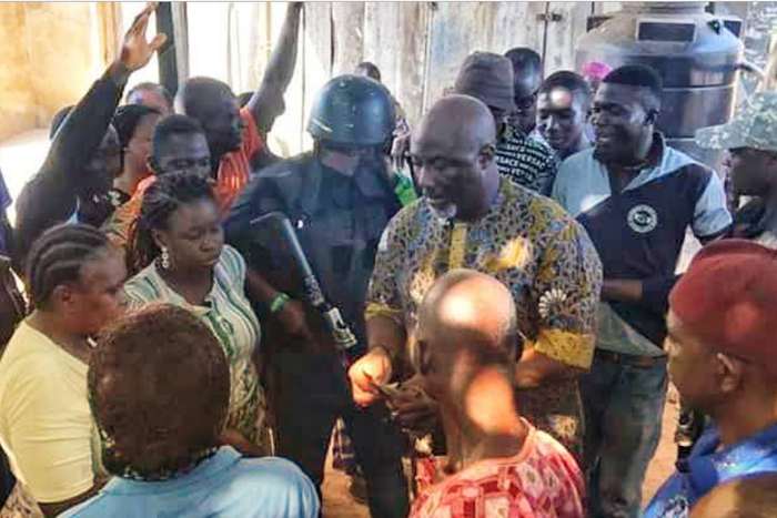Dino Melaye surrounded by his supporters at the shop of a bean cake seller. (Micheal Odoh/Twitter)